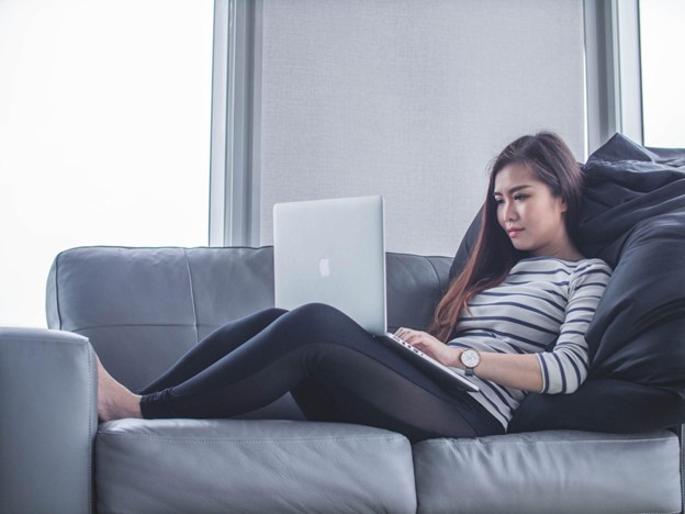 Woman on couch doing online therapy from home