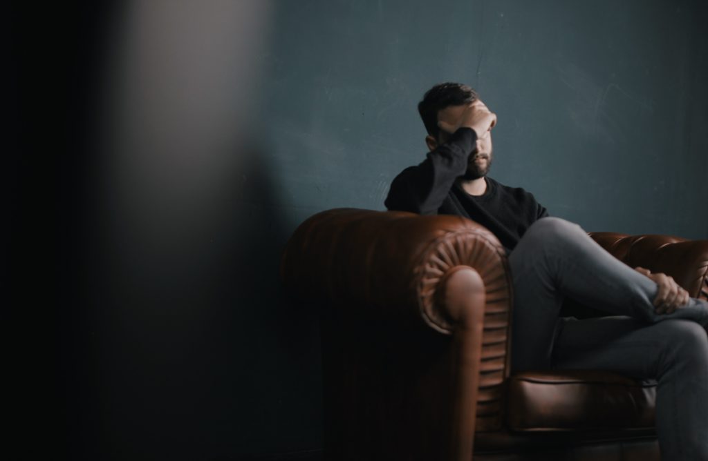 A man sitting on the couch exhausted from emotional abuse